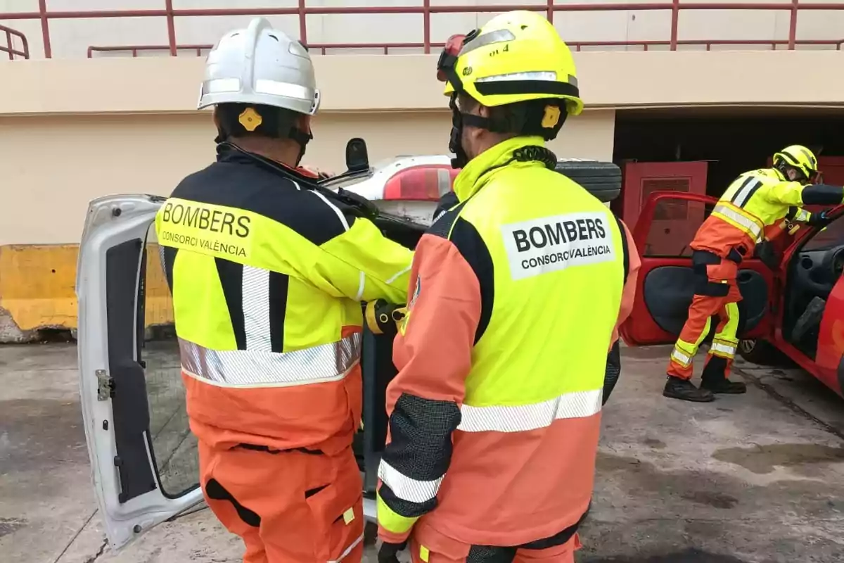 Bomberos con uniformes de alta visibilidad realizan un ejercicio de rescate en un vehículo volcado.