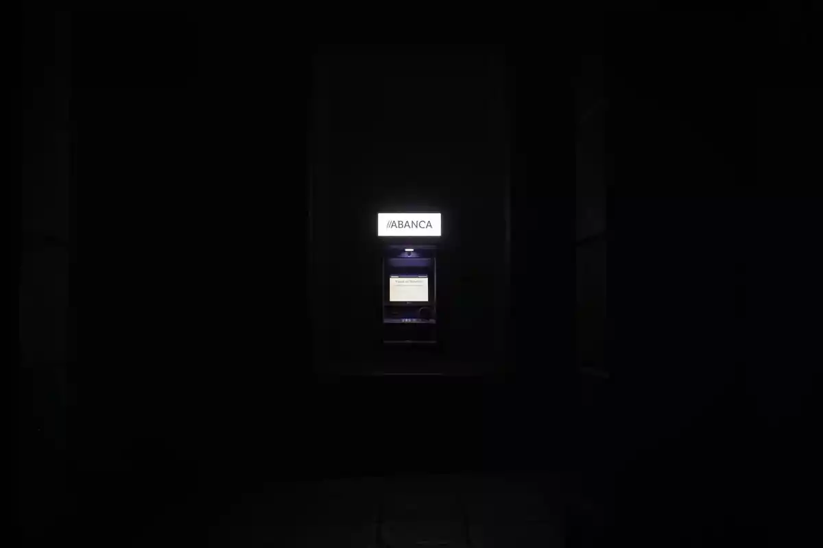 Cajero automático iluminado en medio de la oscuridad Cajero automático iluminado en medio de la oscuridad