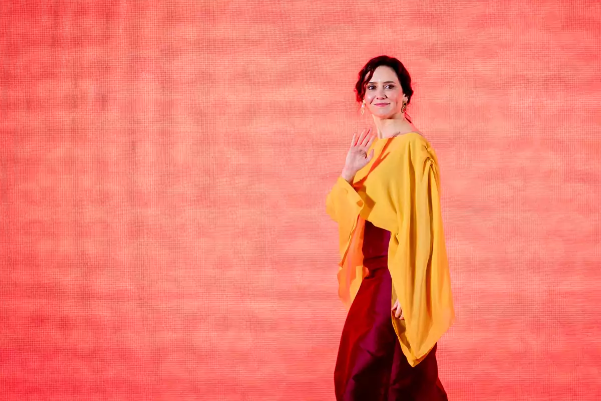 Una persona con vestido amarillo y rojo sobre un fondo rojo.