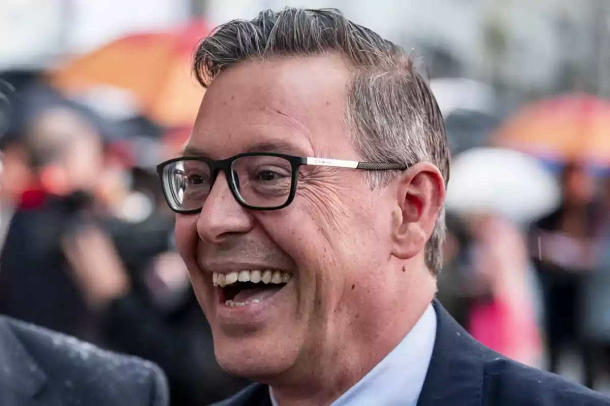 Un hombre con gafas sonriendo ampliamente en un entorno urbano. Un hombre con gafas sonriendo ampliamente en un entorno urbano.