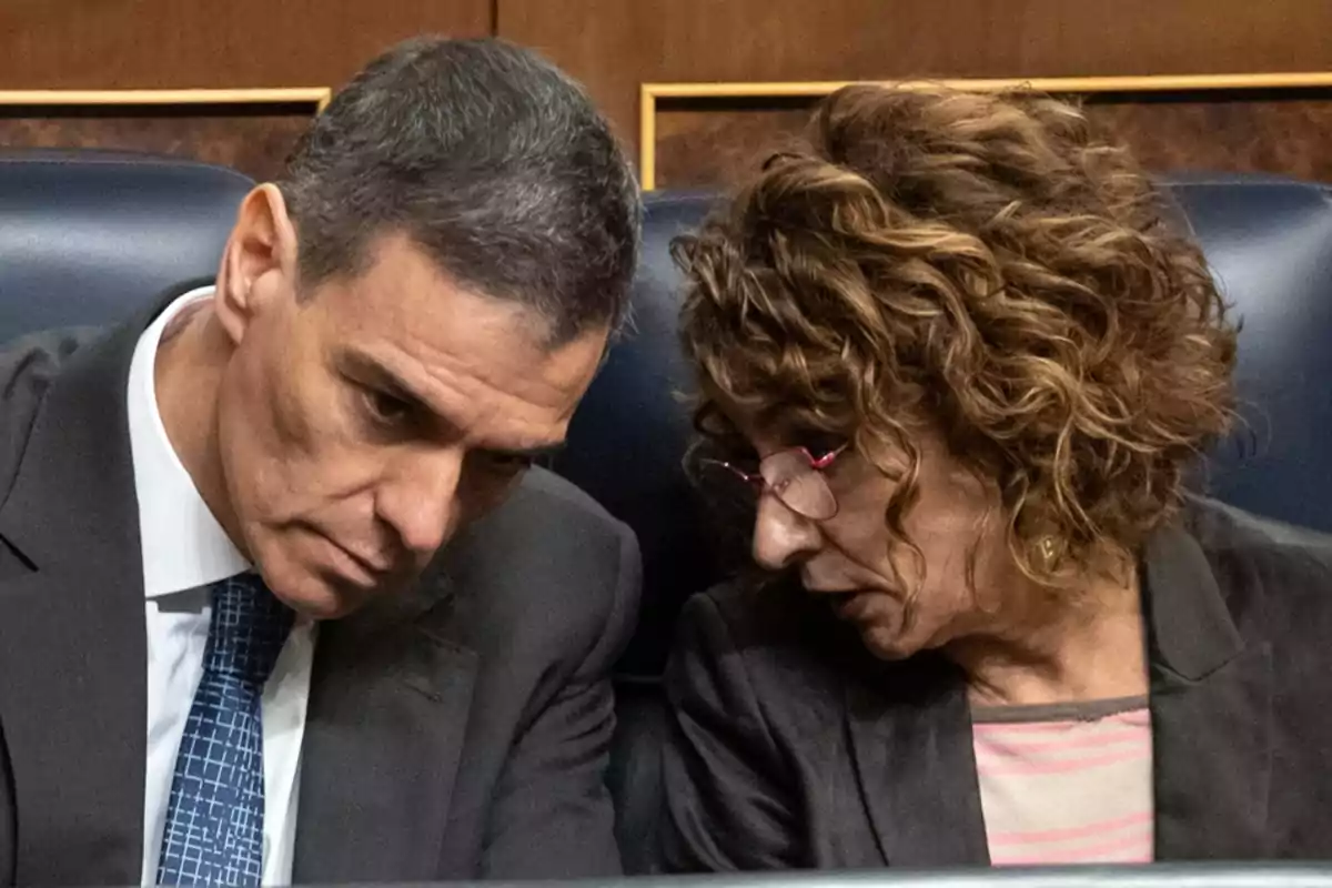 Dos personas sentadas conversando en un entorno formal Dos personas sentadas conversando en un entorno formal