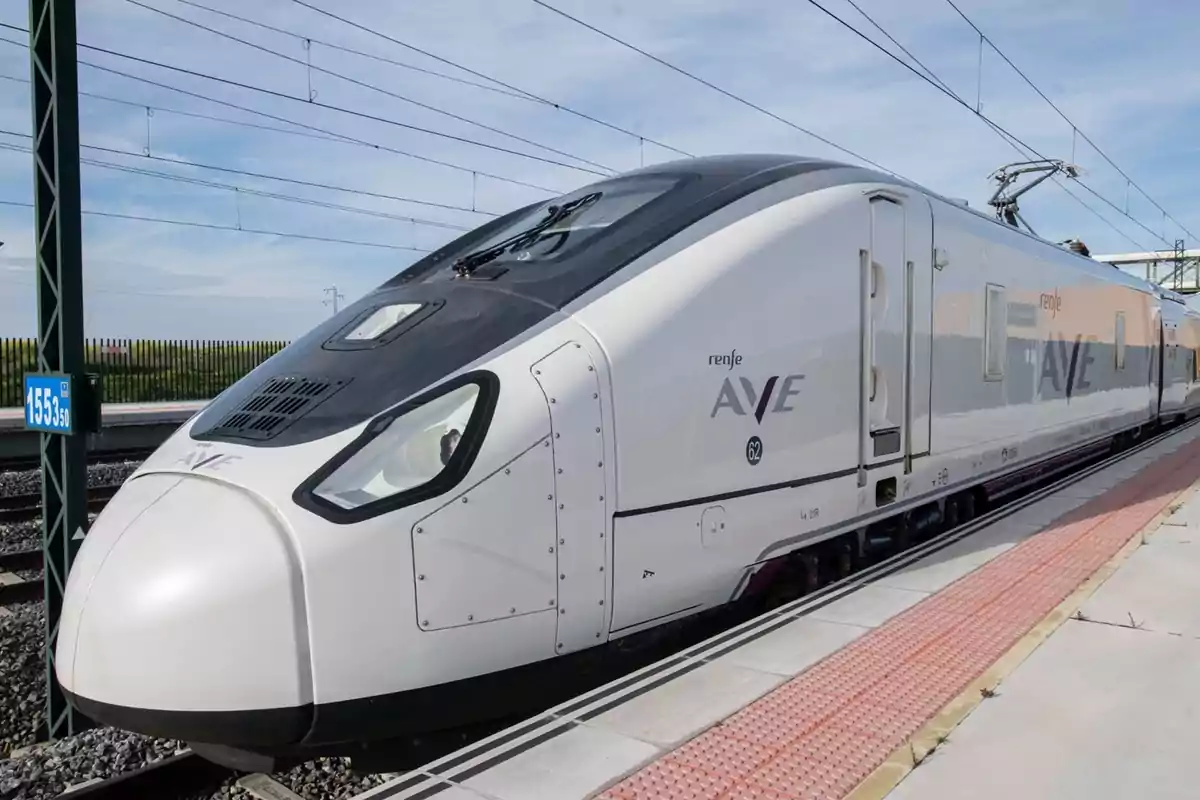 Tren de alta velocidad AVE de Renfe detenido en una estación junto a un andén Tren de alta velocidad AVE de Renfe detenido en una estación junto a un andén