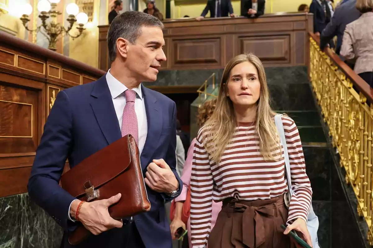 Dos personas caminando por unas escaleras en un edificio con decoración elegante y barandillas doradas. Dos personas caminando por unas escaleras en un edificio con decoración elegante y barandillas doradas.