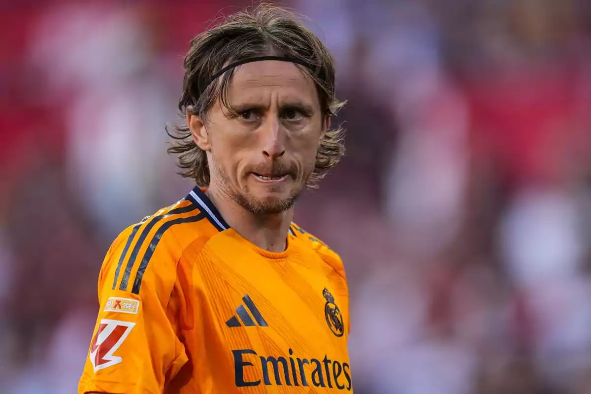 Un jugador de fútbol con uniforme naranja del Real Madrid en el campo. Un jugador de fútbol con uniforme naranja del Real Madrid en el campo.