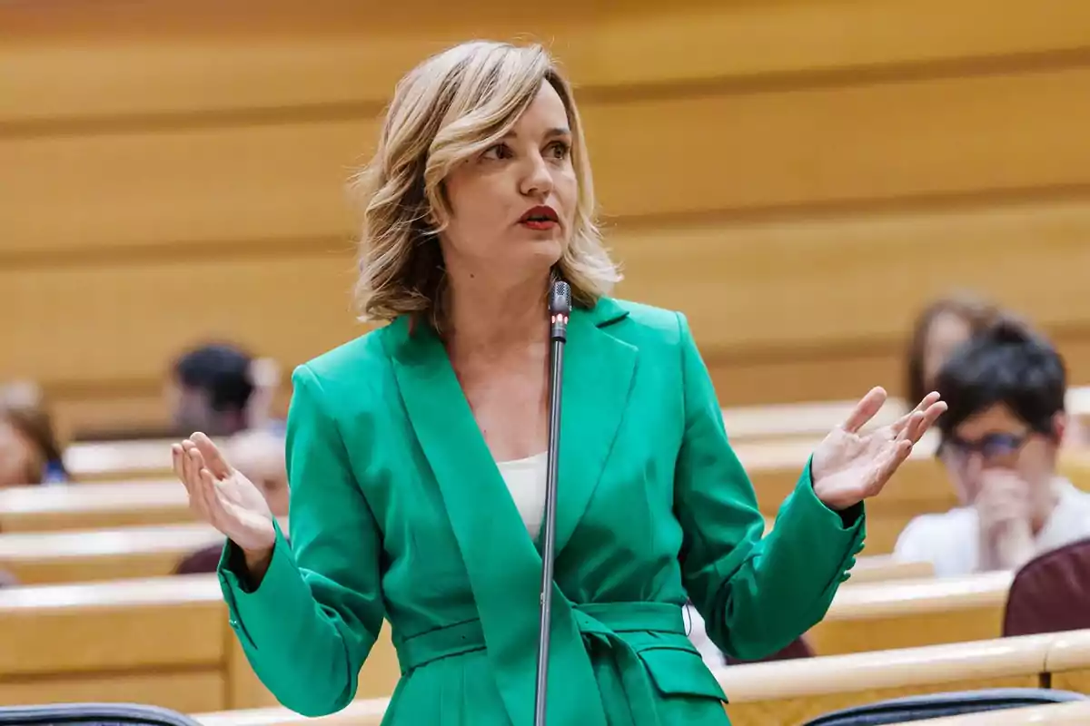 Una persona con un traje verde hablando en un podio en un entorno formal.