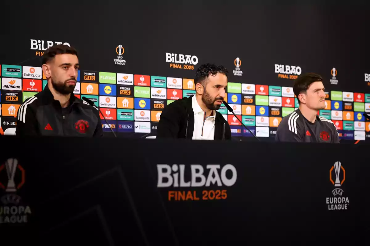 Tres personas en una conferencia de prensa de la UEFA Europa League en Bilbao, con un fondo de logotipos de patrocinadores. Tres personas en una conferencia de prensa de la UEFA Europa League en Bilbao, con un fondo de logotipos de patrocinadores.