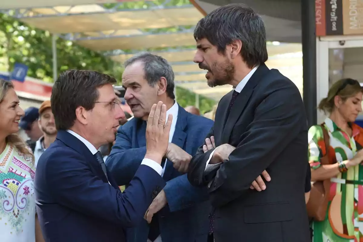 Varias personas conversan al aire libre en un evento formal mientras otras observan alrededor