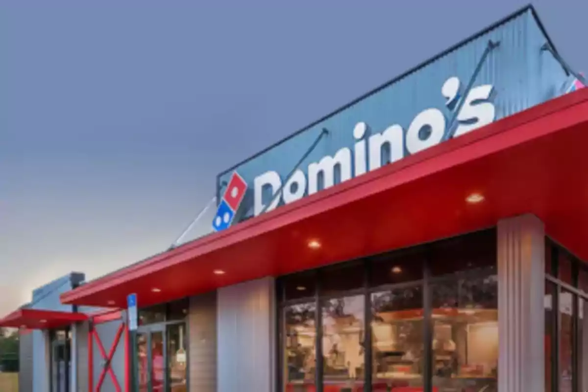 Fachada de una pizzería con un letrero grande y un techo rojo. Fachada de una pizzería con un letrero grande y un techo rojo.