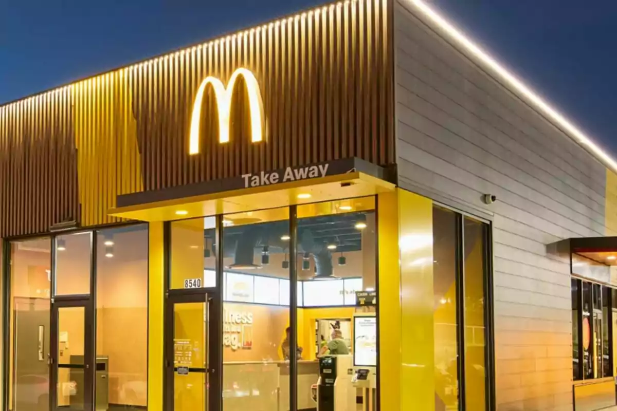 Fachada de un restaurante de comida rápida con un gran logotipo amarillo iluminado en la parte superior. Fachada de un restaurante de comida rápida con un gran logotipo amarillo iluminado en la parte superior.