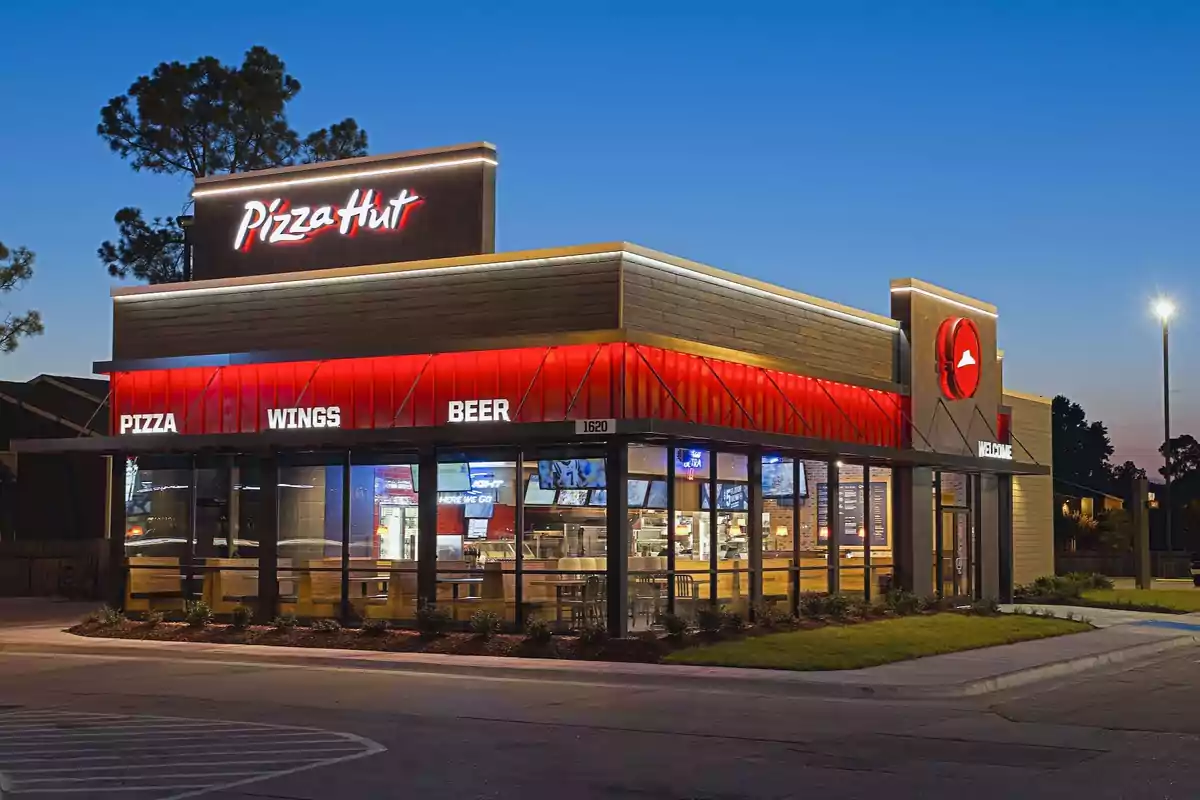 A fast-food restaurant with a modern design and bright lights on the exterior during sunset. A fast-food restaurant with a modern design and bright lights on the exterior during sunset.