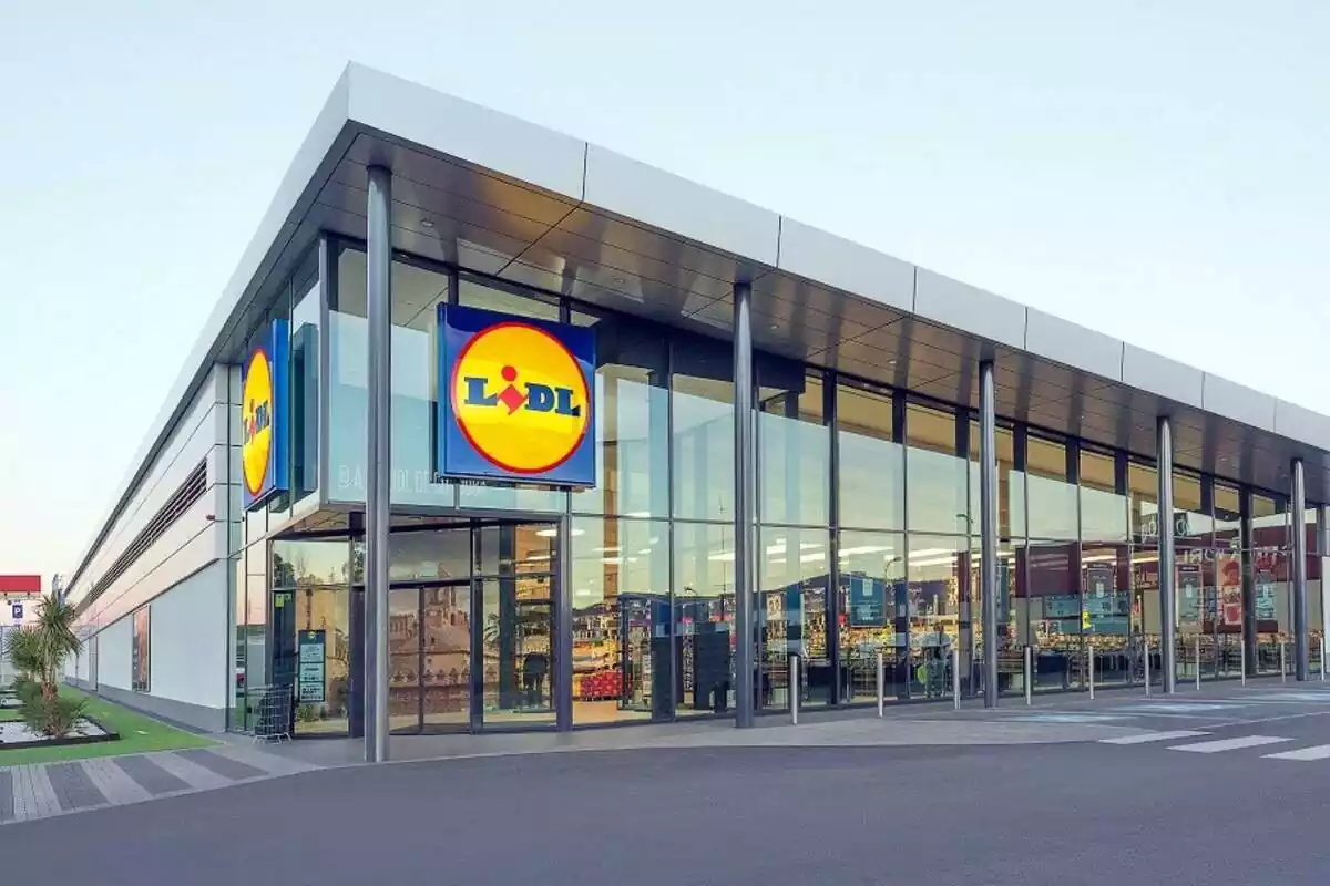 Vista exterior de una nueva tienda de Lidl en España con 2 logos a la vista y luz en el interior Vista exterior de una nueva tienda de Lidl en España con 2 logos a la vista y luz en el interior