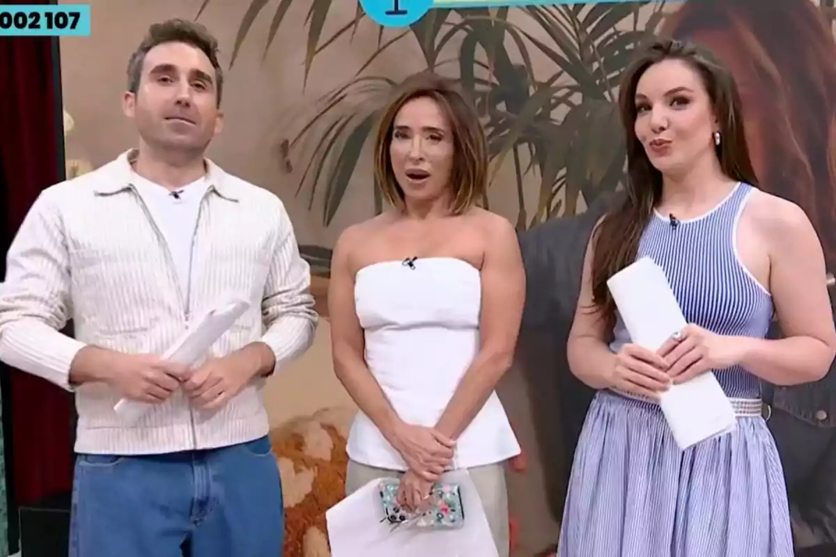 Tres presentadores de televisión, Aitor Albizua, María Patiño e Inés Hernand, posan juntos en un set decorado de La Familia de la Tele con plantas y un fondo beige, cada uno sostiene papeles en las manos y visten ropa casual y elegante Tres presentadores de televisión, Aitor Albizua, María Patiño e Inés Hernand, posan juntos en un set decorado de La Familia de la Tele con plantas y un fondo beige, cada uno sostiene papeles en las manos y visten ropa casual y elegante