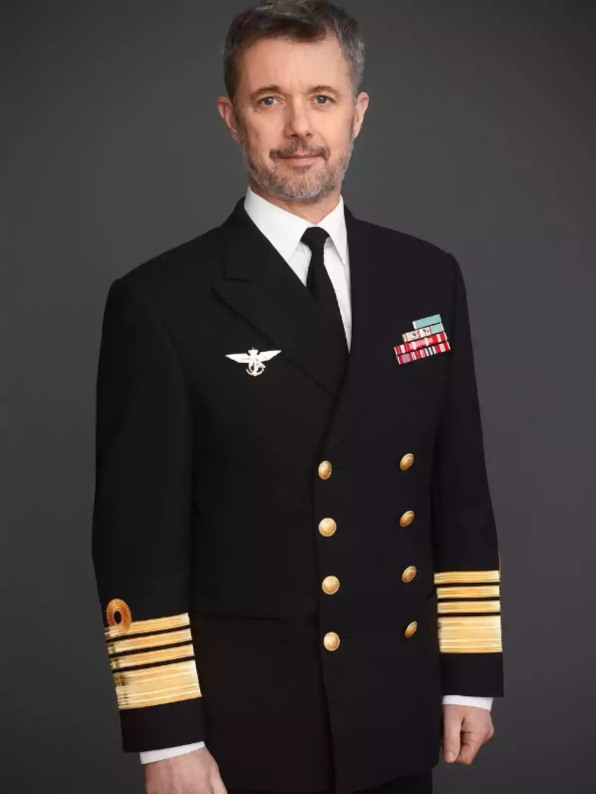 Middle-aged man with a beard and short hair dressed in a dark military uniform with gold buttons and decorations against a gray background Middle-aged man with a beard and short hair dressed in a dark military uniform with gold buttons and decorations against a gray background