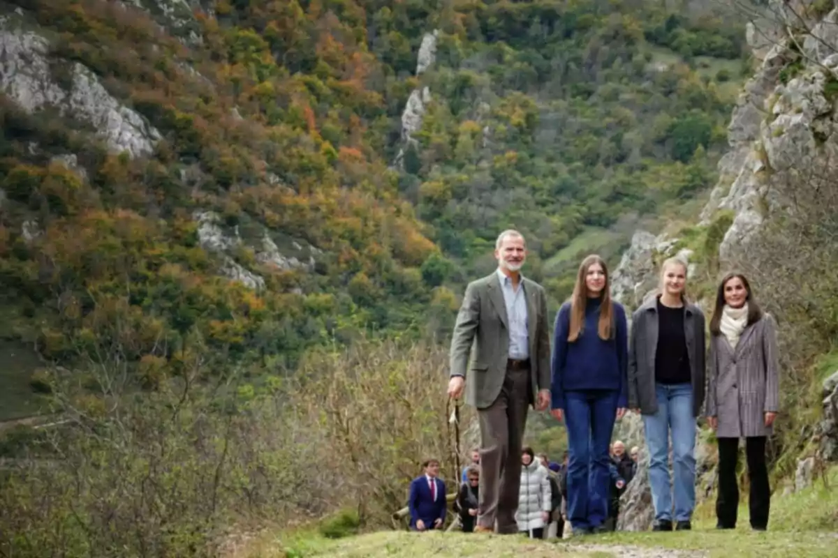 Un grupo de personas camina por un sendero rodeado de montañas y vegetación en un entorno natural. Un grupo de personas camina por un sendero rodeado de montañas y vegetación en un entorno natural.