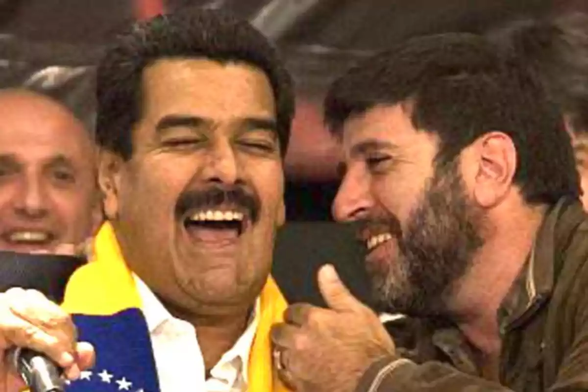 Dos personas riendo y conversando en un evento público. Dos personas riendo y conversando en un evento público.