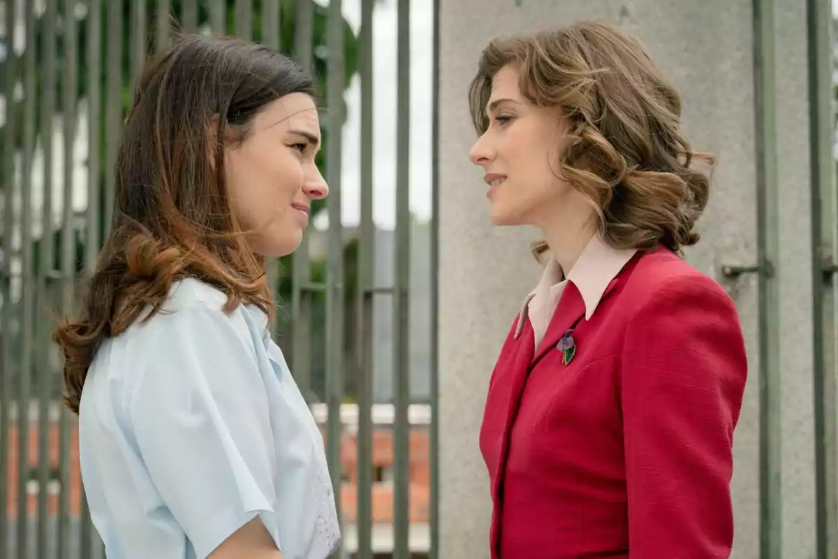 Fotografía de Marta Belmonte y Alba Brunet frente a una reja, una vestida con una camisa blanca y la otra con un traje rojo en Sueños de Libertad