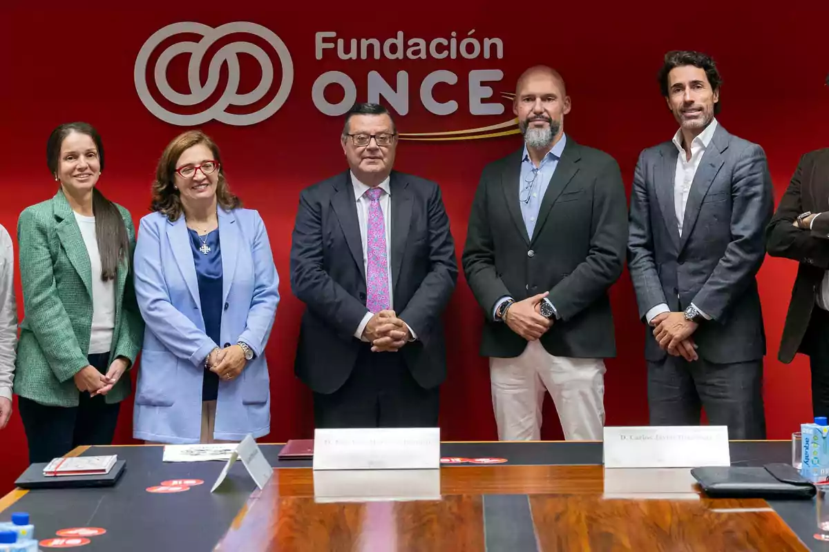 Un grupo de personas posando frente a un fondo rojo con el logo de la Fundación ONCE.