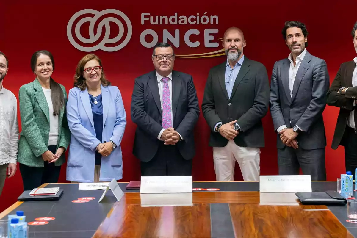 Un grupo de personas posando frente a un fondo rojo con el logo de la Fundación ONCE.