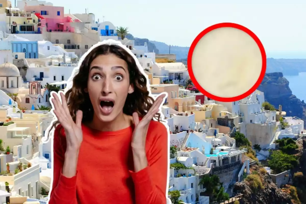 Una mujer sorprendida con las manos en el rostro sobre un fondo de casas blancas y coloridas en una colina junto al mar, con un círculo rojo resaltando un área borrosa.