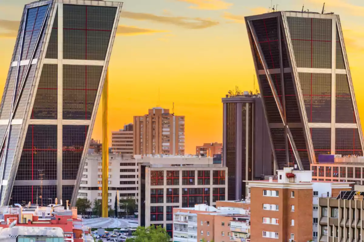 Torres inclinadas en una ciudad al atardecer con edificios de fondo.