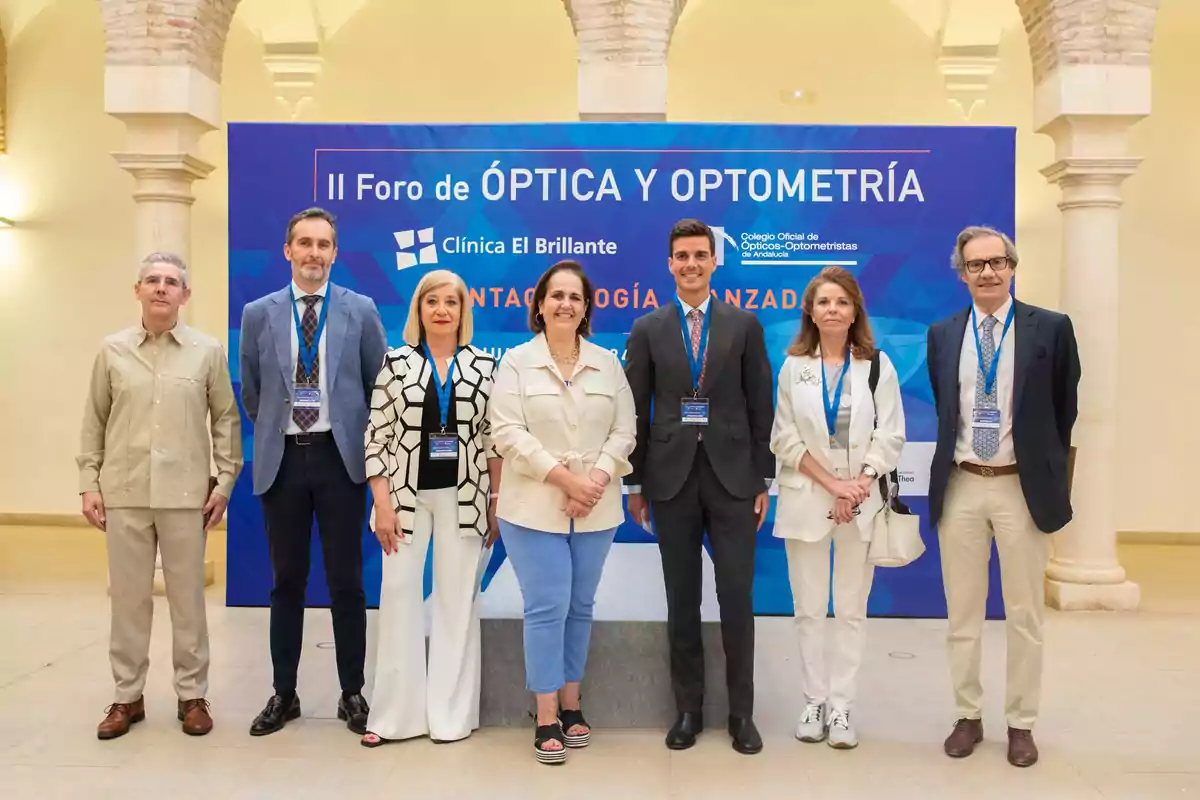 Personas posando frente a un cartel del II Foro de Óptica y Optometría de la Clínica El Brillante.