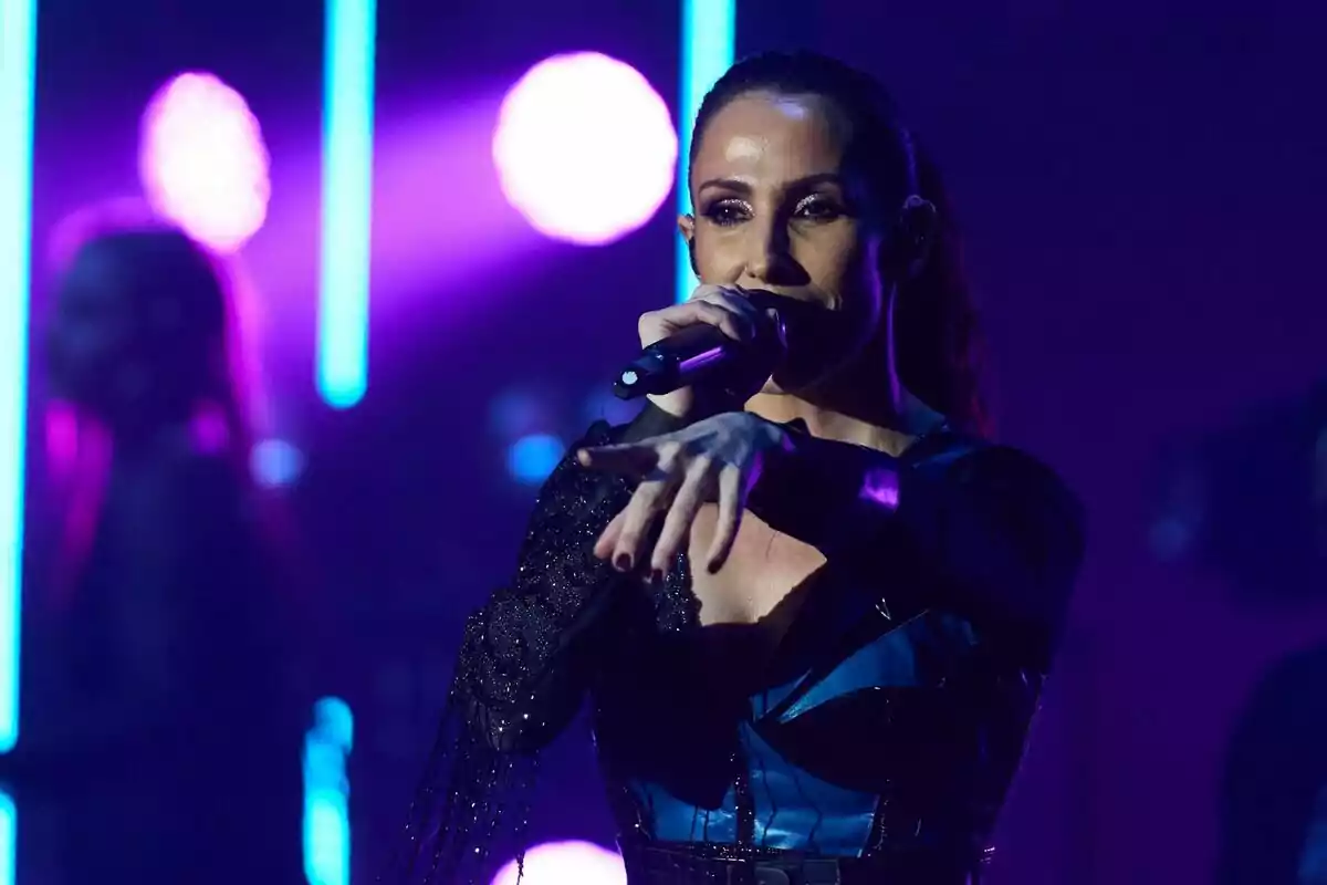 Foto de Malú cantando durante uno de sus conciertos mientras señala al público con la mano. Foto de Malú cantando durante uno de sus conciertos mientras señala al público con la mano.
