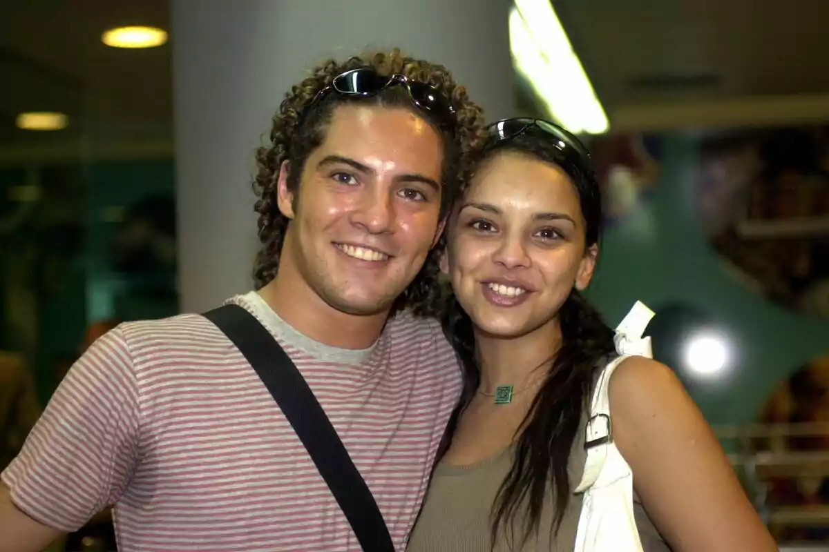 David Bisbal y Chenoa sonriendo y posando para una foto en un entorno interior.