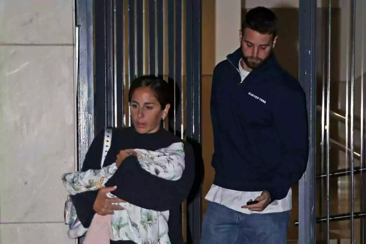 Anabel Pantoja and David Rodríguez exit a building, Anabel carrying a baby wrapped in a blanket.