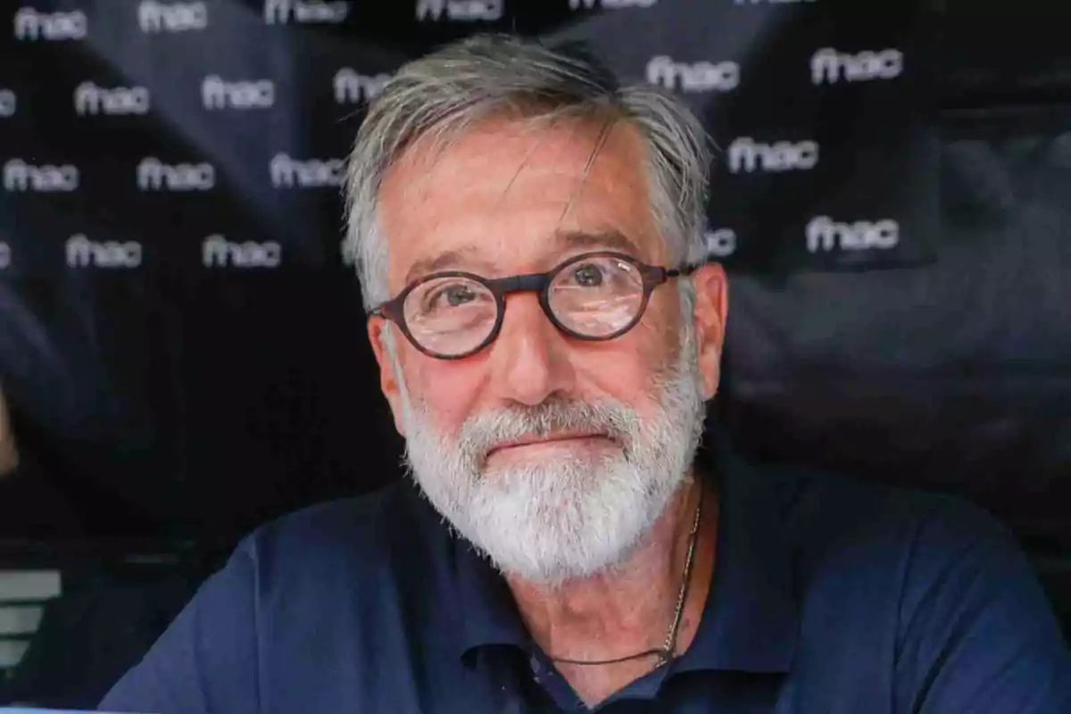 Emilio Aragón con barba y gafas redondas sonríe levemente frente a un fondo con logotipos de fnac Emilio Aragón con barba y gafas redondas sonríe levemente frente a un fondo con logotipos de fnac
