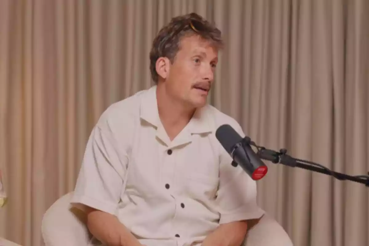 Grison con bigote y camisa clara sentado frente a un micrófono durante una entrevista Grison con bigote y camisa clara sentado frente a un micrófono durante una entrevista
