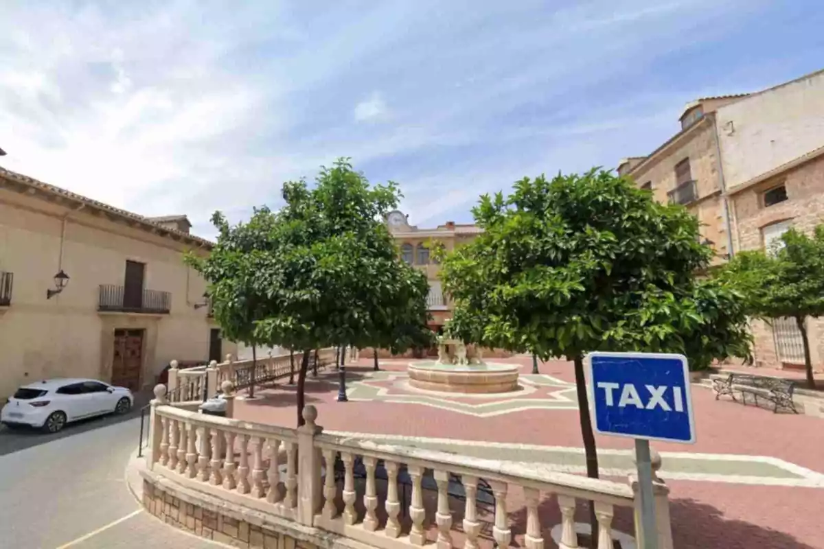 Plaza con árboles, una fuente central, bancos y un letrero azul de taxi en primer plano en Sorihuela del Guadalimar Plaza con árboles, una fuente central, bancos y un letrero azul de taxi en primer plano en Sorihuela del Guadalimar