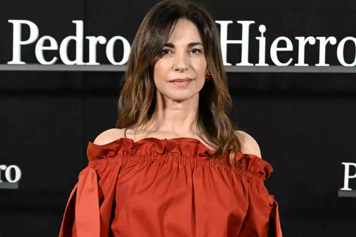 Mariló Montero with loose brown hair is wearing a red off-the-shoulder blouse against a black background with white text.