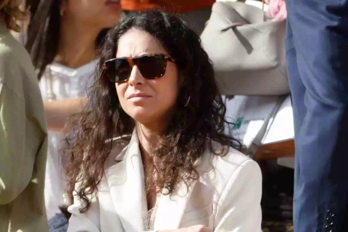 Xisca Perelló with sunglasses and curly hair is wearing a light blazer while outdoors. Xisca Perelló with sunglasses and curly hair is wearing a light blazer while outdoors.