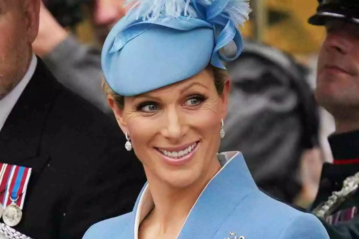 Zara Tindall smiling with a light blue hat adorned with feathers. Zara Tindall smiling with a light blue hat adorned with feathers.