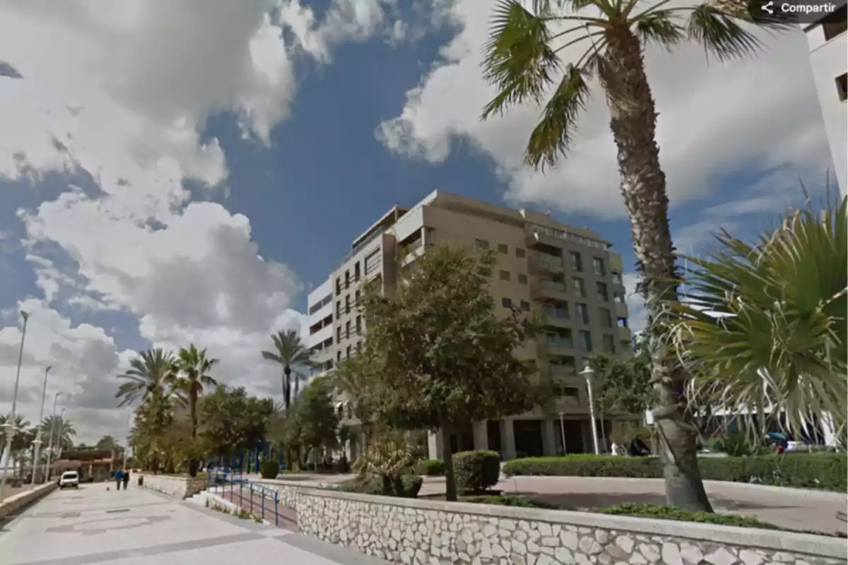 Edificio moderno de varios pisos rodeado de palmeras y árboles junto a una acera amplia bajo un cielo parcialmente nublado en el barrio de San Andrés, Málaga Edificio moderno de varios pisos rodeado de palmeras y árboles junto a una acera amplia bajo un cielo parcialmente nublado en el barrio de San Andrés, Málaga
