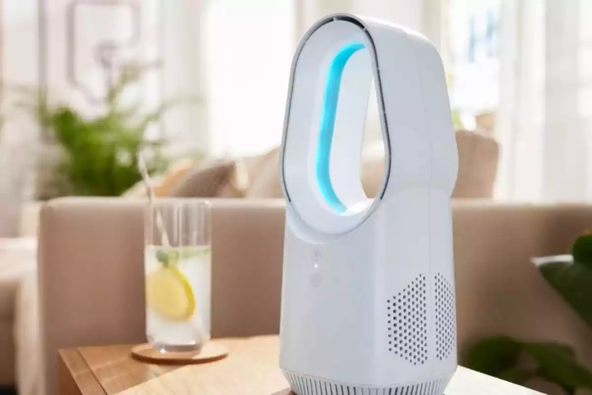 Ventilador moderno sin aspas sobre una mesa junto a un vaso de agua con rodaja de limón en una sala iluminada. Ventilador moderno sin aspas sobre una mesa junto a un vaso de agua con rodaja de limón en una sala iluminada.