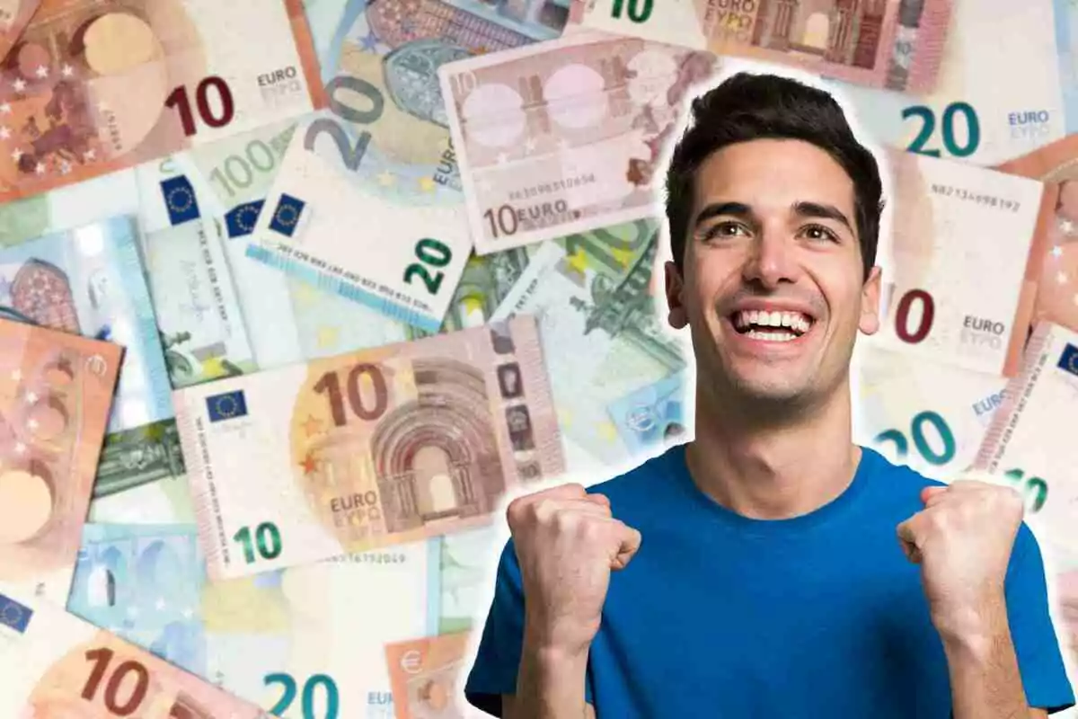 Hombre sonriente con camiseta azul celebrando frente a un fondo de billetes de euro.