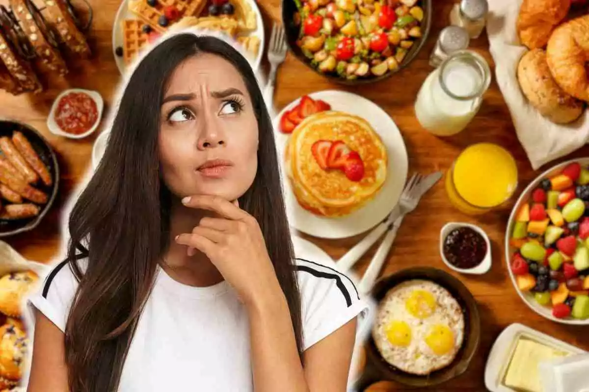 Mujer pensativa frente a una mesa llena de opciones de desayuno como panqueques, frutas, huevos y jugo.