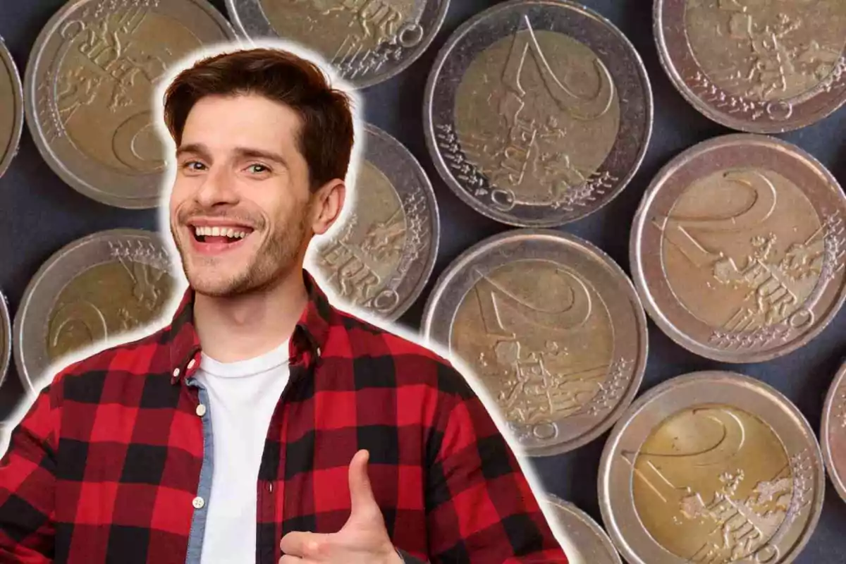 Un hombre sonriente con una camisa de cuadros rojos y negros hace un gesto de aprobación con el pulgar hacia arriba, con un fondo de monedas de dos euros.