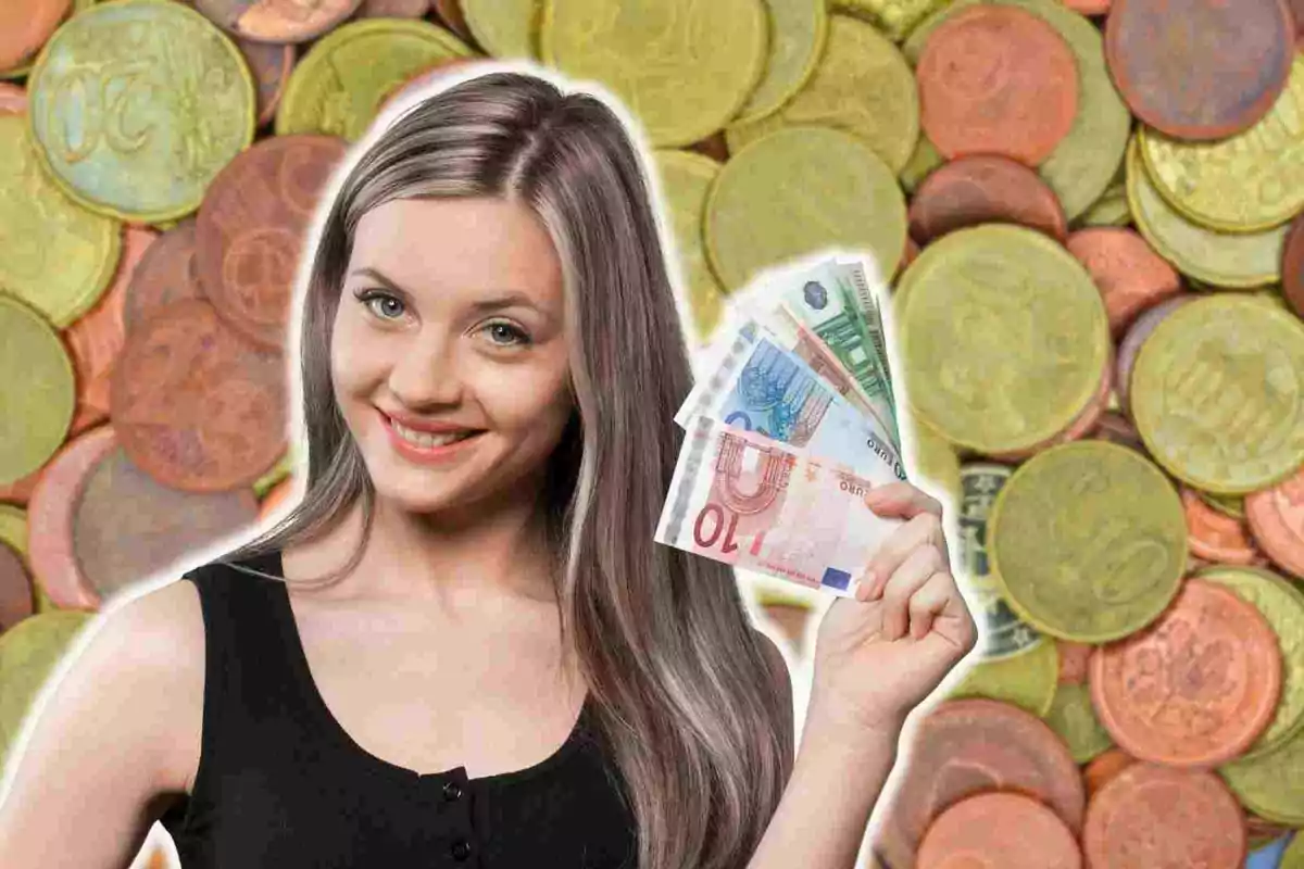 Una mujer sonriente sostiene billetes de euro frente a un fondo de monedas.