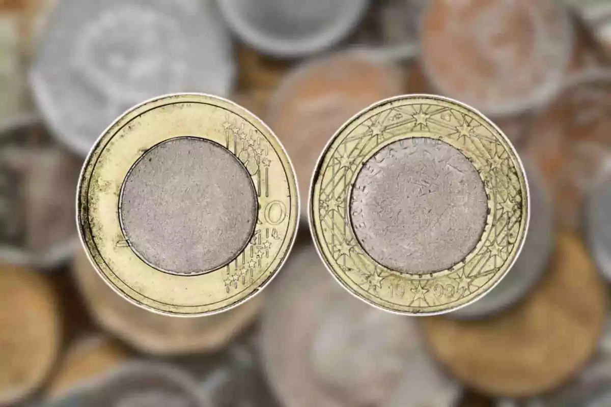 Dos monedas de euro sobre un fondo borroso de otras monedas. Dos monedas de euro sobre un fondo borroso de otras monedas.