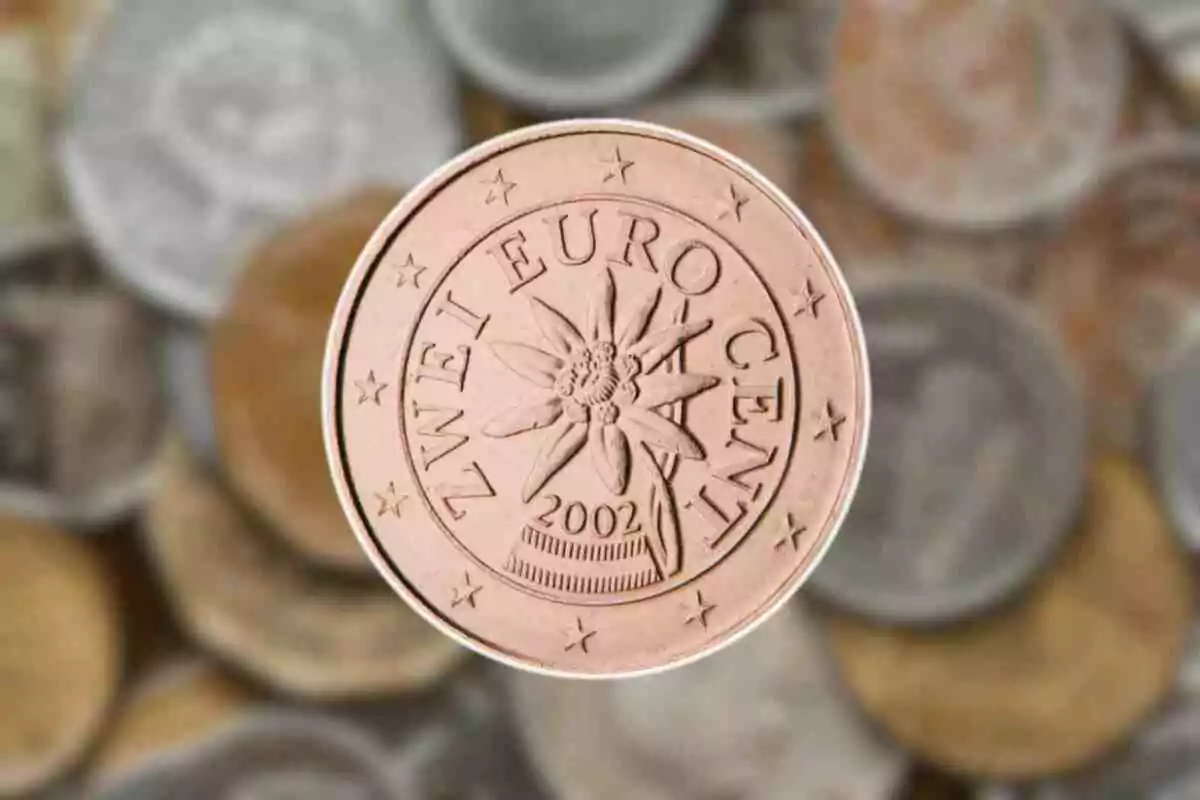 Moneda de dos céntimos de euro con diseño de flor edelweiss y fondo de otras monedas desenfocadas. Moneda de dos céntimos de euro con diseño de flor edelweiss y fondo de otras monedas desenfocadas.