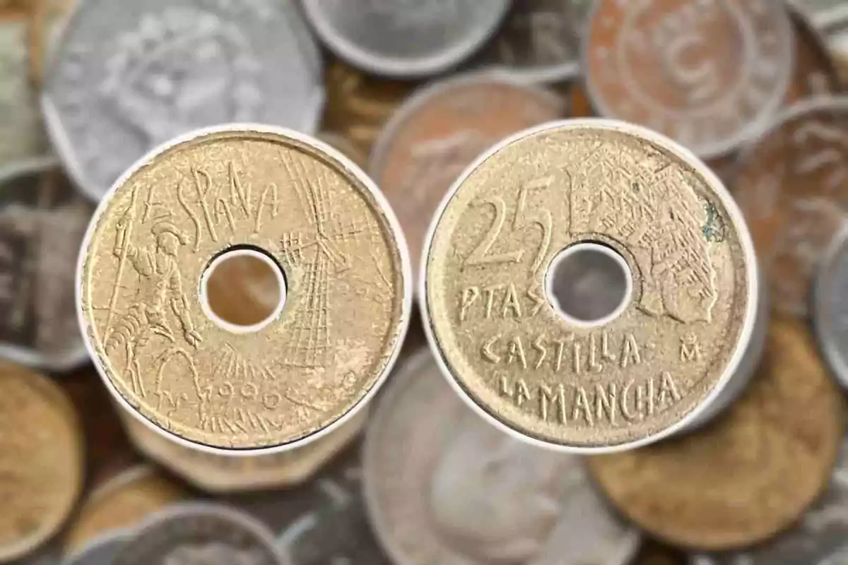 Monedas antiguas de 25 pesetas de España con un agujero en el centro y fondo de otras monedas desenfocadas. Monedas antiguas de 25 pesetas de España con un agujero en el centro y fondo de otras monedas desenfocadas.