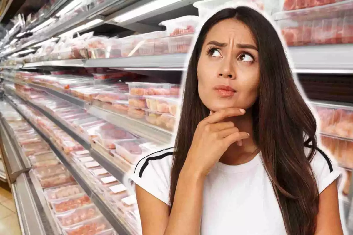 Mujer pensativa en un pasillo de supermercado lleno de productos envasados.