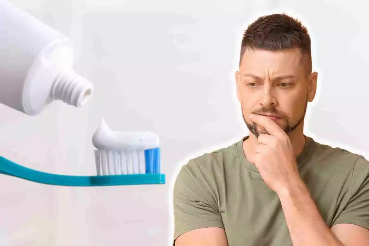 Un hombre pensativo observa un cepillo de dientes con pasta dental.