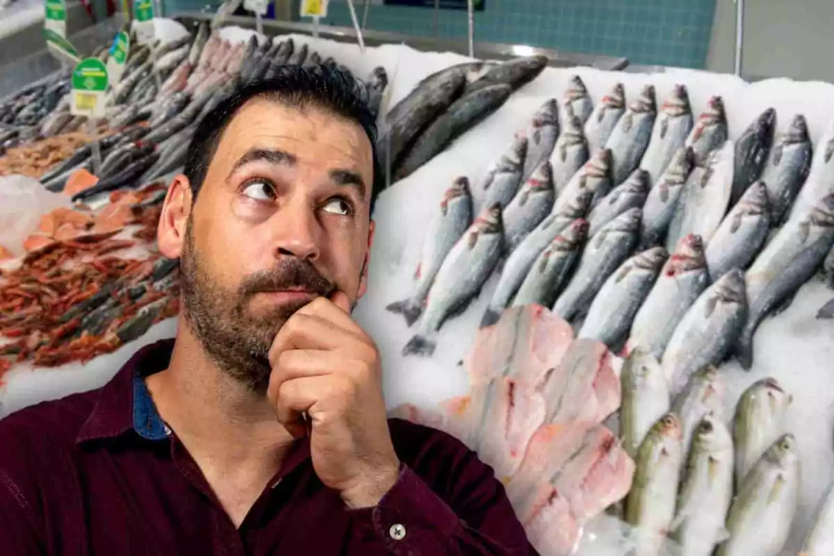 Hombre pensativo frente a un mostrador de pescados y mariscos en un mercado.