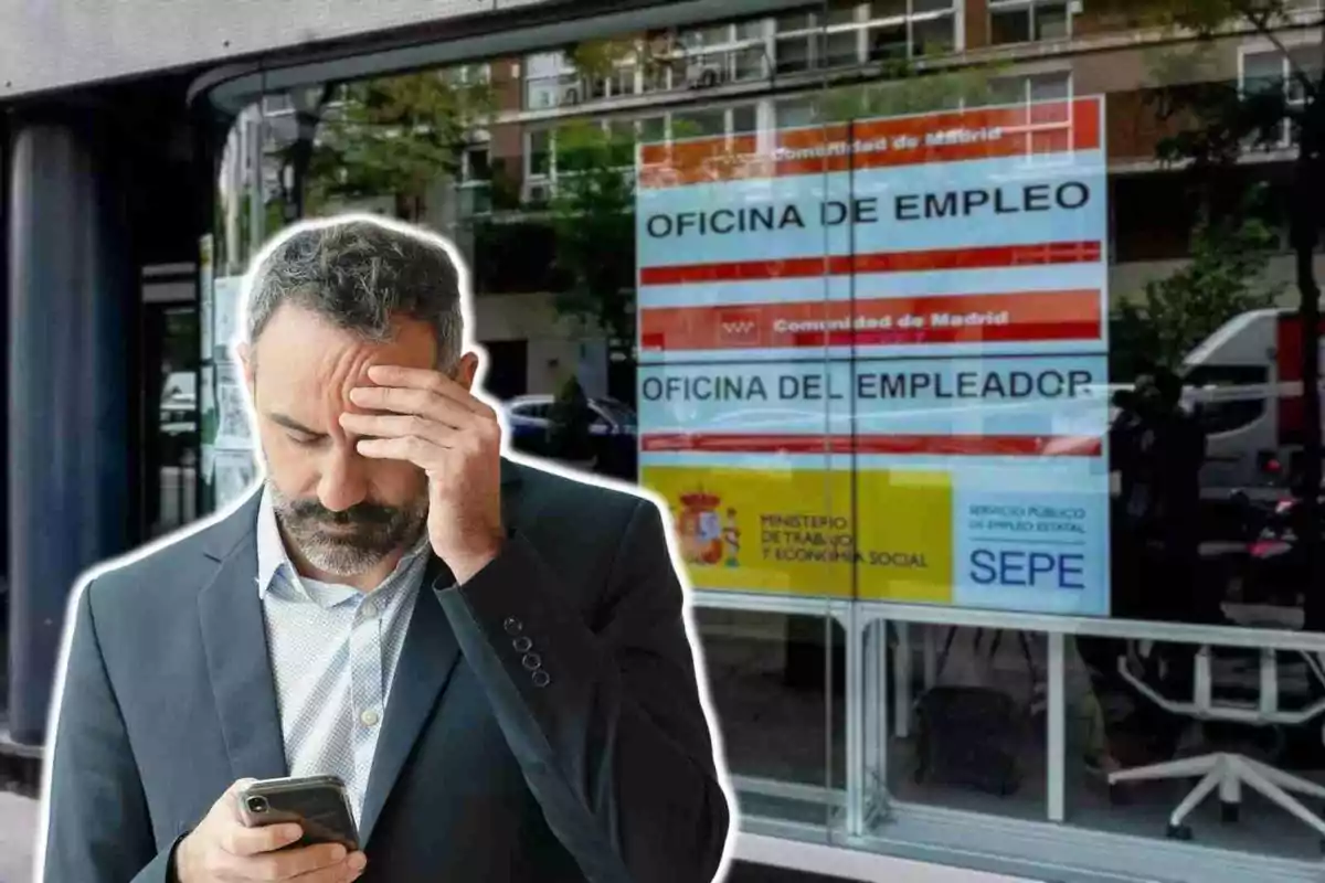 Un hombre con traje y gesto preocupado mira su teléfono frente a una oficina de empleo en Madrid.