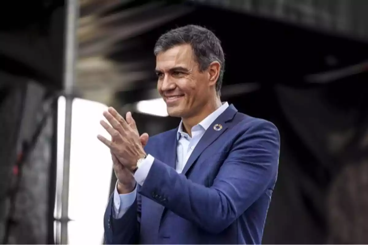 Un hombre con traje azul aplaudiendo y sonriendo en un entorno urbano. Un hombre con traje azul aplaudiendo y sonriendo en un entorno urbano.