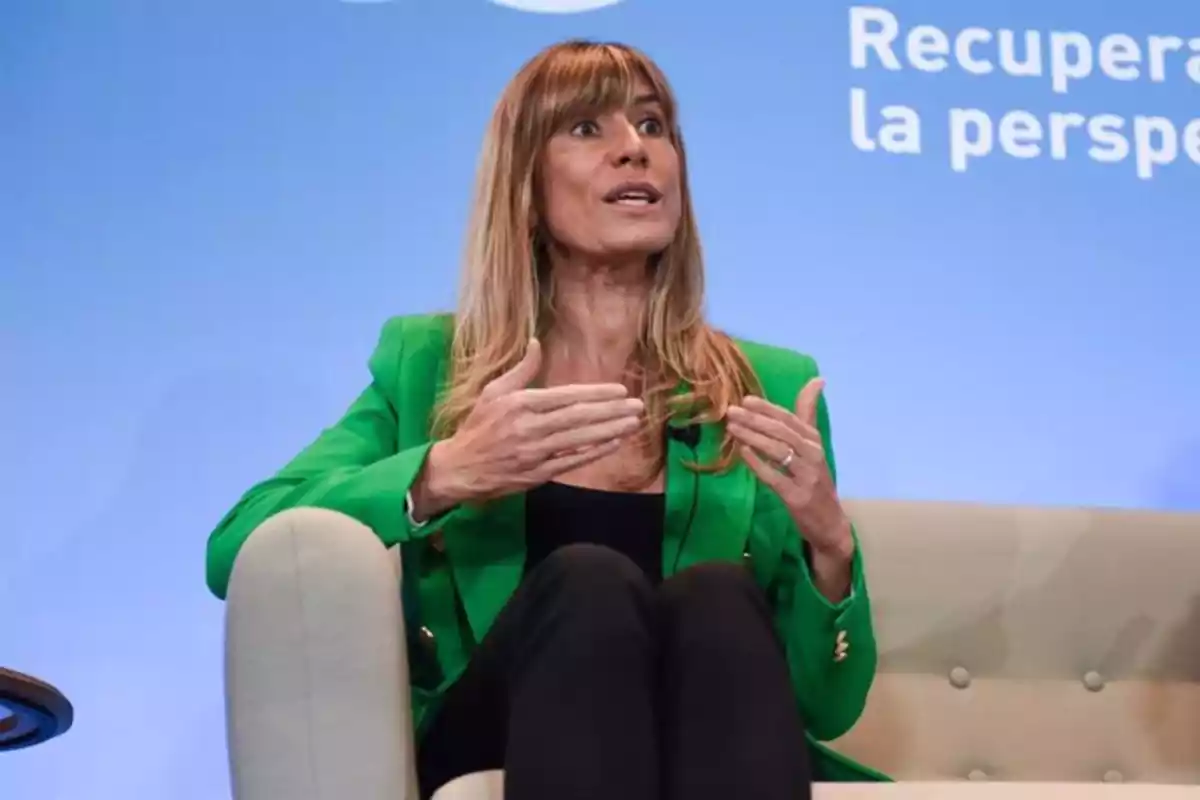 Mujer con chaqueta verde hablando gesticulando con las manos en un evento con fondo azul. Mujer con chaqueta verde hablando gesticulando con las manos en un evento con fondo azul.