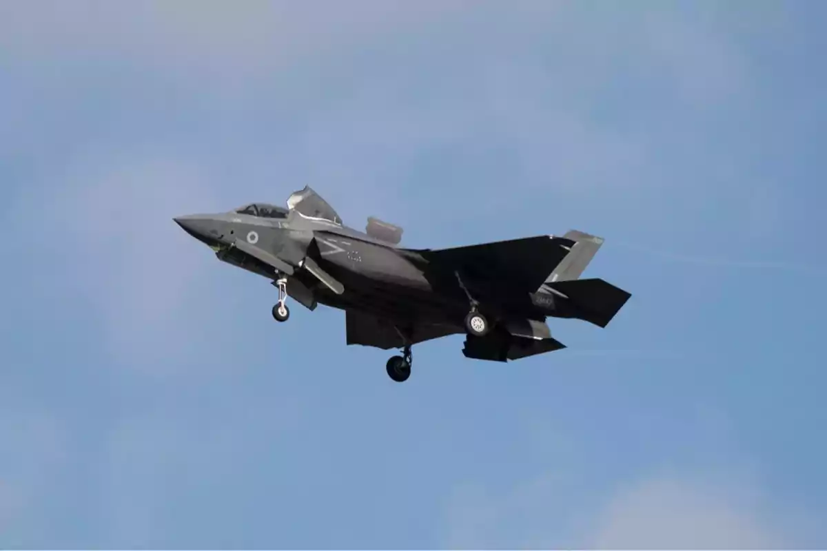 Avión de combate militar volando con el tren de aterrizaje desplegado sobre un cielo azul Avión de combate militar volando con el tren de aterrizaje desplegado sobre un cielo azul